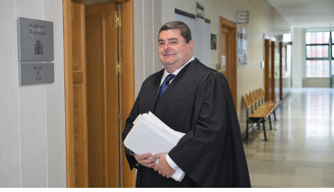 Abogado penalista con toga en pasillos del Tribunal de Instancia preparando la defensa en un caso de denuncia falsa y simulación de delito.